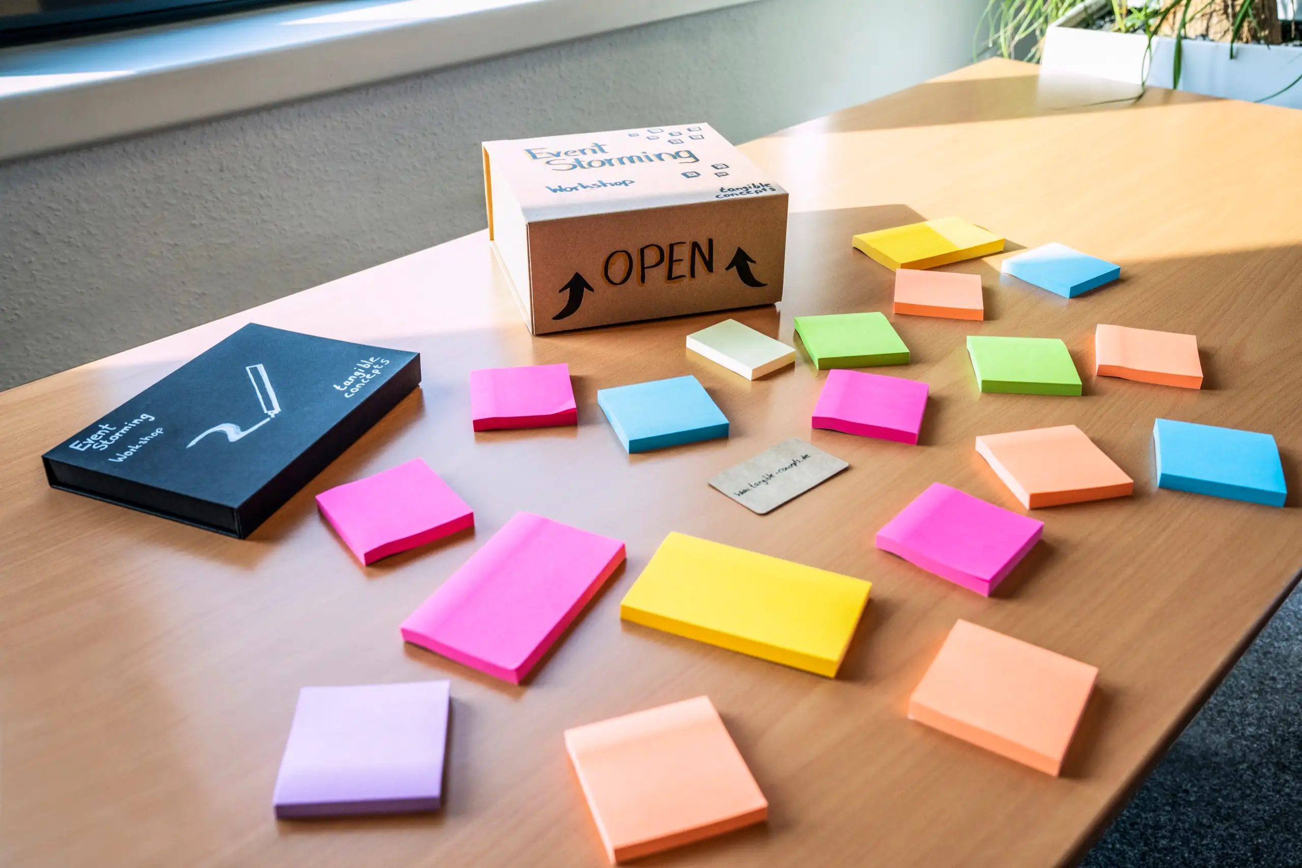 Bunte Sticky-Note-Blöcke und eine Box mit der Aufschrift OPEN auf einem Holztisch, bereit für einen Workshop