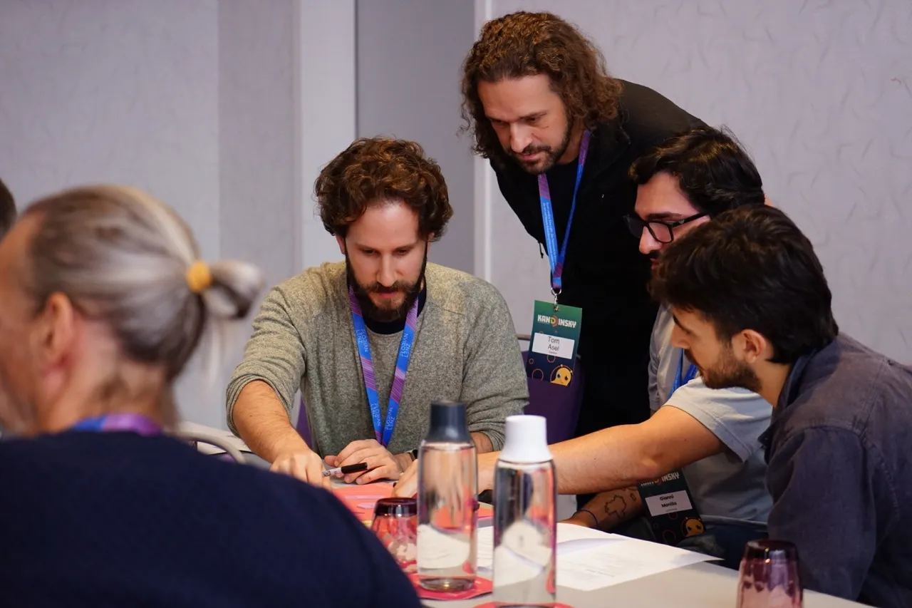 Team arbeitet kollaborativ an Modellierung mit digitalen Geräten und Workshop-Materialien